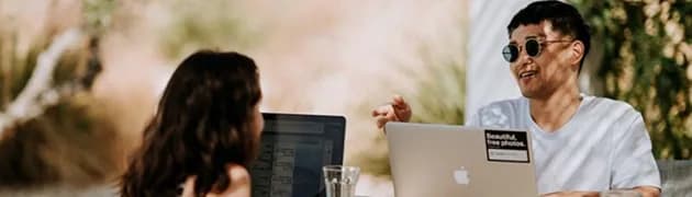 Two people clarifying a deliverable at their laptops