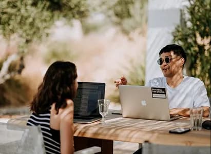 Two colleagues discussing a milestone at their laptops